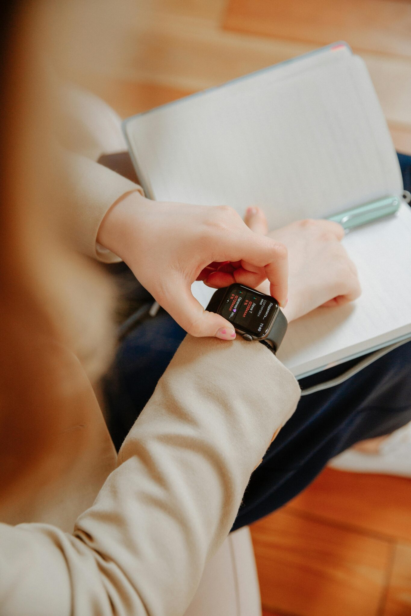 Close-up of a woman wearing a smartwatch and writing in a notebook indoors.